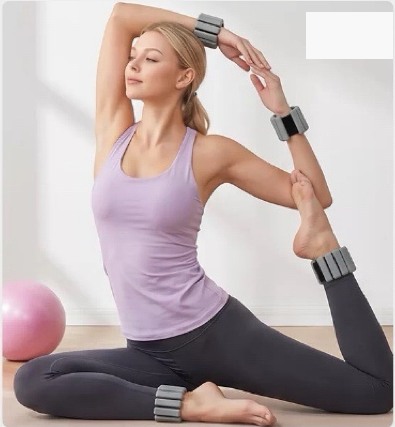 Woman using segmented silicone wrist and ankle weights during controlled Pilates training