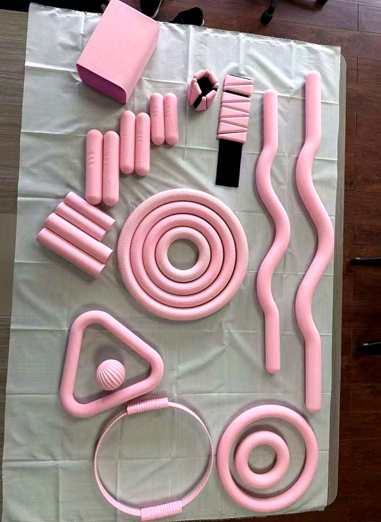 Pink Pilates accessories and silicone wrist weights arranged as a studio equipment collection